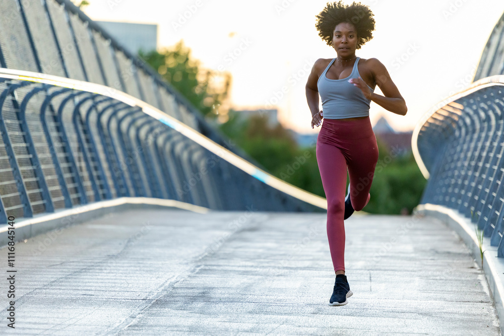 Female black athlete stride running outdoors in Boston bridge Female black athlete stride running outdoors in Boston bridge