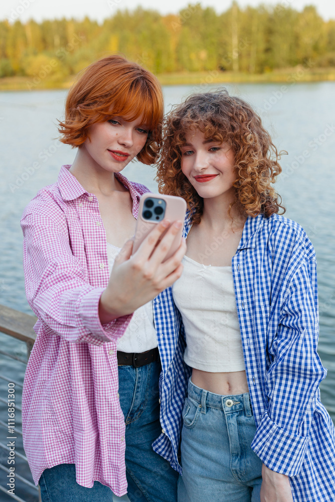 Two friends taking a selfie by the lakeside during a sunny day Two friends taking a selfie by the lakeside during a sunny day