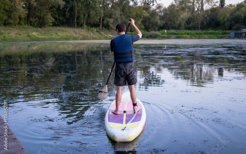 Man paddleboarding on a SUP board in a pond photo