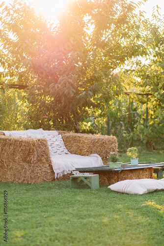 Sunlit outdoor seating area with hay bale furniture. photo