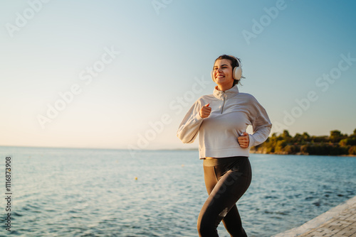 Young caucasian woman running or jogging on the beach at sunset 