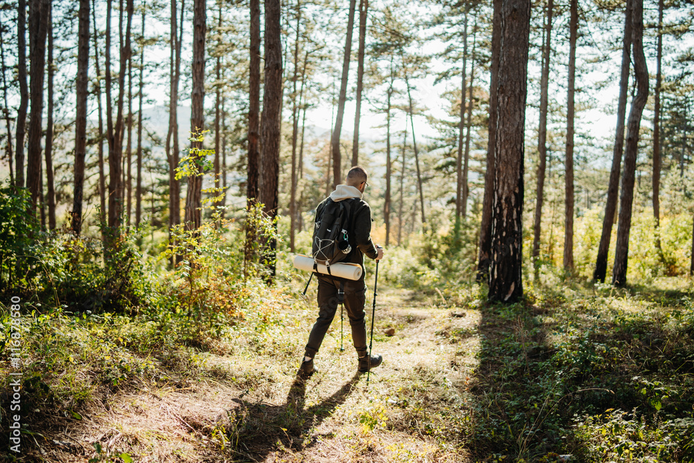 Obraz premium Young caucasian man hiking or trekking through the forest 