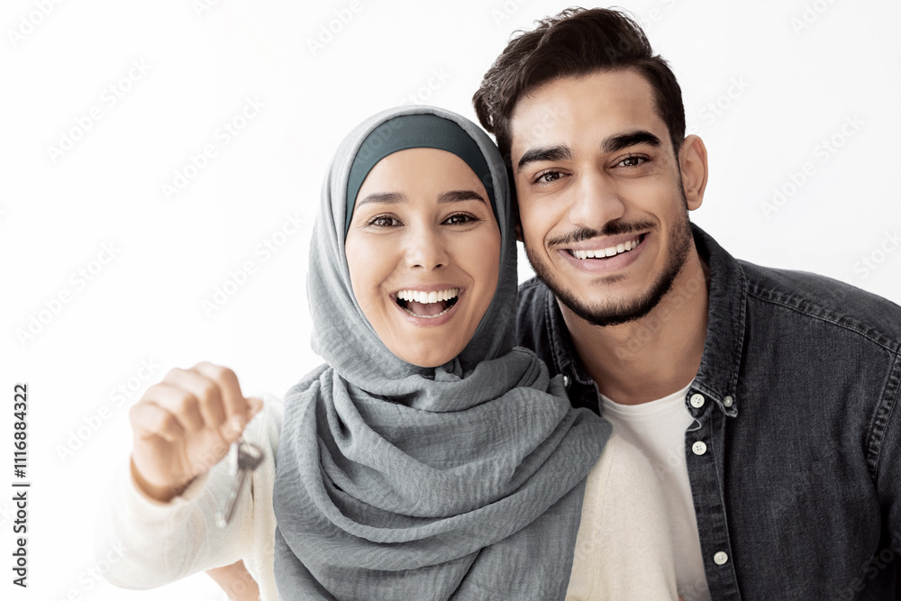 Emotional young lady in hijab showing key from new house, standing by her husband, copy space. Happy muslim family embracing in their brand new apartment, paper boxes with belongings on background Emotional young lady in hijab showing key from new house, standing by her husband, copy space. Happy muslim family embracing in their brand new apartment, paper boxes with belongings on background