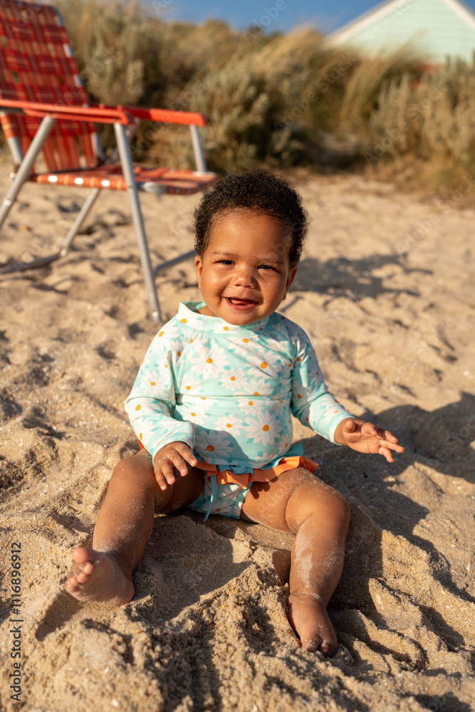 A baby laughing at the camera sitting on the sand at the beach A baby laughing at the camera sitting on the sand at the beach