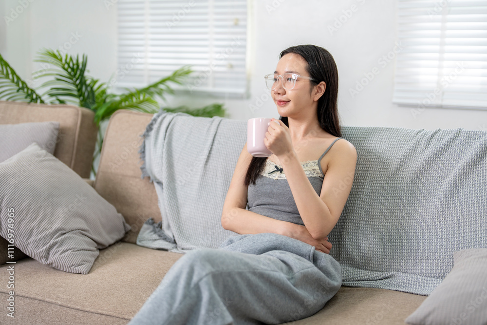 Young woman relaxing on sofa drinking coffee and looking away Young woman relaxing on sofa drinking coffee and looking away
