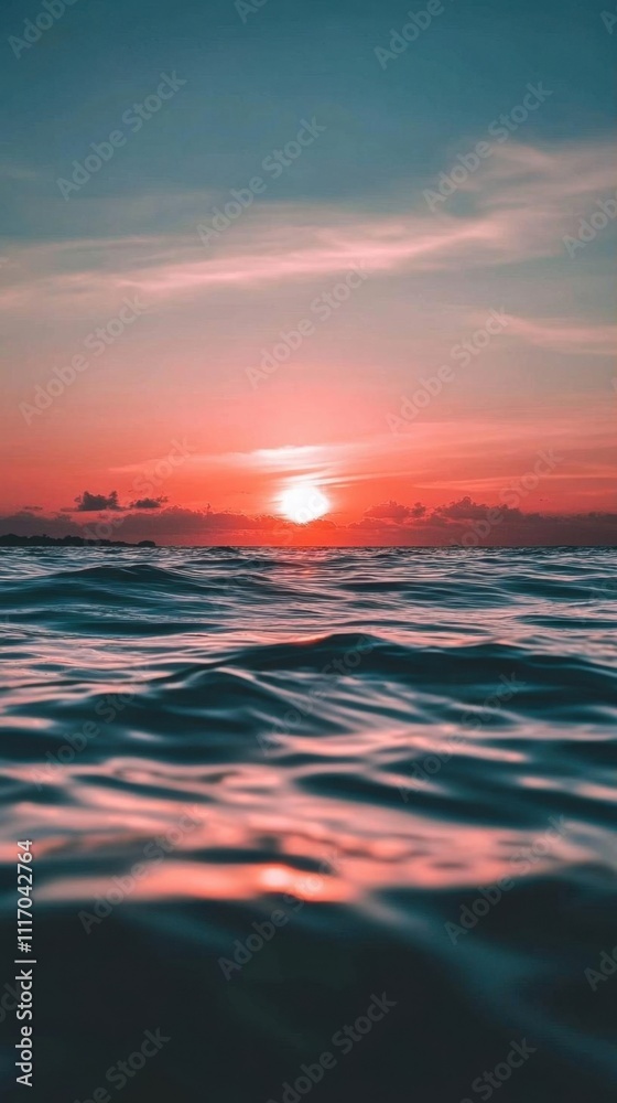 Fototapeta premium A serene sunset over calm ocean waters, reflecting warm colors.