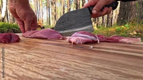 man cutting meat on cutting board in forest