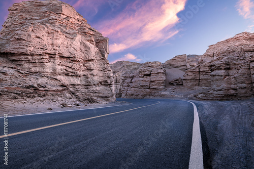 Asphalt road and mountain natural landscape at dusk in Xinjiang. Road trip in no man's land. Famous Dahaidao desert gobi scenery in China. photo