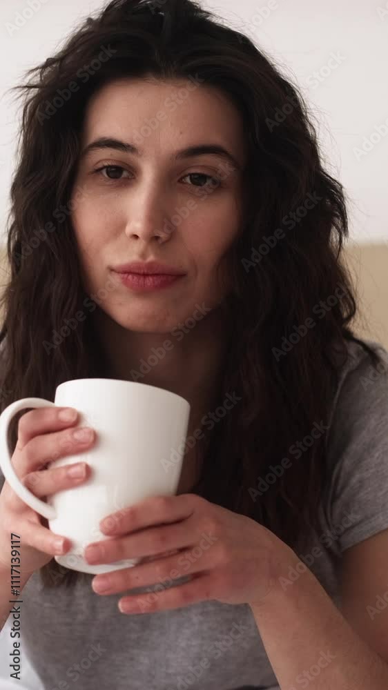 Vertical video. Sleepy morning. Coffee energy. Insomnia disorder. Tired sleepless woman drinking cup of latte on soft bed in light bedroom. Vertical video. Sleepy morning. Coffee energy. Insomnia disorder. Tired sleepless woman drinking cup of latte on soft bed in light bedroom.