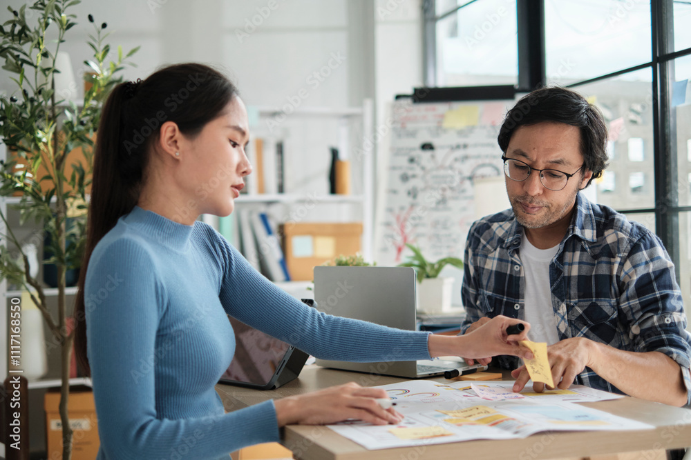 © tigercat_lpg - Two young Asian startup company partners discuss and brainstorm in casual small business office, marketing planning jobs on a desk, and freelance work as E-commerce entrepreneur and coworker team. © tigercat_lpg - Two young Asian startup company partners discuss and brainstorm in casual small business office, marketing planning jobs on a desk, and freelance work as E-commerce entrepreneur and coworker team.