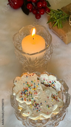 A jar with homemade Christmas cookies, gifts and lit candle on the table. Christmas dessert concept.