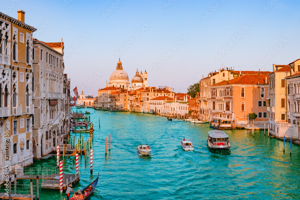 June 25, 2019. Venice, Italy. Beautiful view of traditional Gondola on famous Canal Grande with Basilica di Santa Maria della Salute in golden evening light at sunset in Venice, Italy.