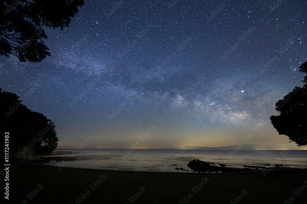 森の先にある浜辺から見る天の川と能登半島の星空