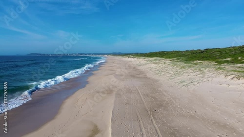 Drone aerial pan of ocean sea morning waves breaking on sandy beach with dune plantation restoration landscape Central Coast Australia travel nature tourism photo