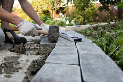 Obraz na płótnie Laying paving stones on cement mortar. Laying a garden path made of tiles. Self-laying of concrete paving slabs in the courtyard of the house. do it yourself. DIY w salonie