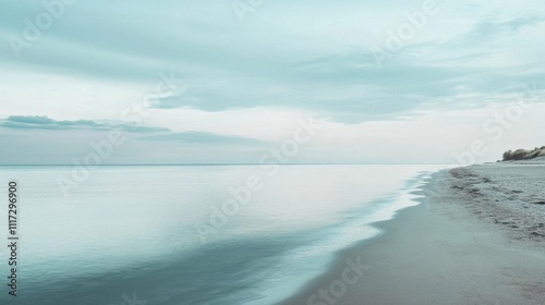 Serene beach landscape with calm water and soft clouds.