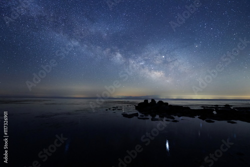 Obraz na płótnie 海の水面にゆれる星と天の川と能登半島の星空 w salonie