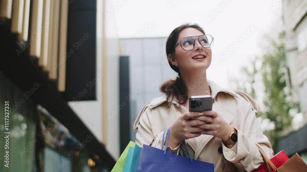Young woman using smartphone and carrying shopping bags