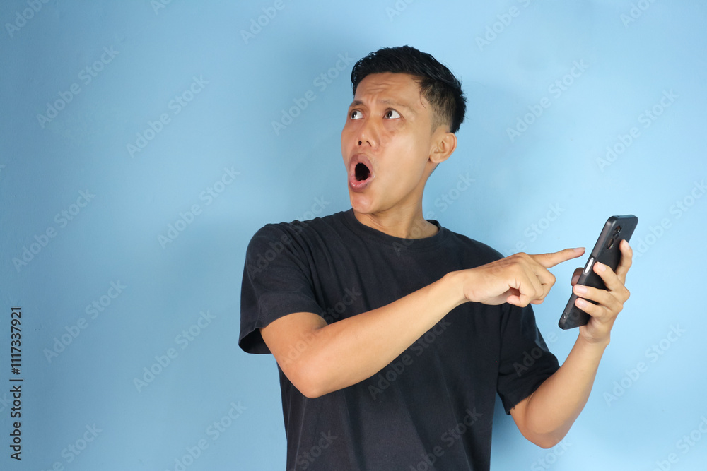Asian man pressing mobile phone with finger feels excited and looks up Asian man pressing mobile phone with finger feels excited and looks up