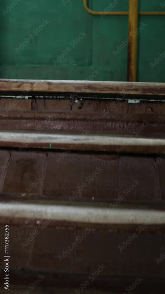 Vertical video. Old wooden brown stairs going up them from the first person. A yellow metal railings. The walls beside the stairs are painted green. With chipped and faded paint Vertical video. Old wooden brown stairs going up them from the first person. A yellow metal railings. The walls beside the stairs are painted green. With chipped and faded paint