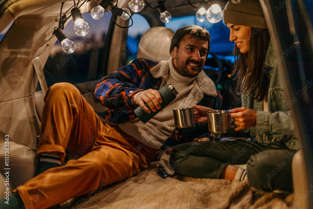 Man and woman sharing hot beverages in a car trunk setup Man and woman sharing hot beverages in a car trunk setup