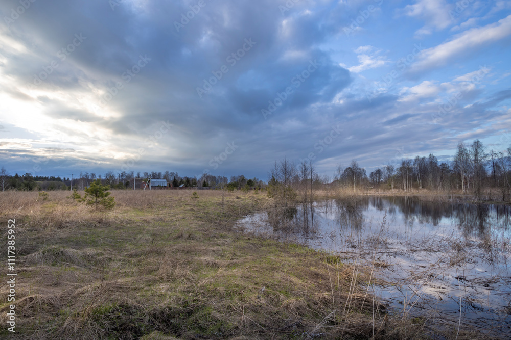 Field with a pond in the middle and a house in the background Field with a pond in the middle and a house in the background