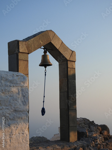 Glocke einer christlichen Kapelle im Sonnenuntergang vor nebelverhangenem Meer photo