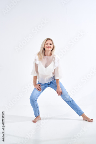 Wallpaper Mural Blonde in a white T-shirt and blue jeans poses in a studio on a white background. Torontodigital.ca