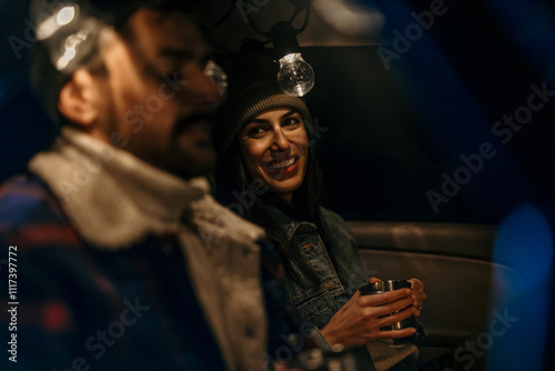 Man and woman enjoying warm drinks in the back of their truck on a cold night