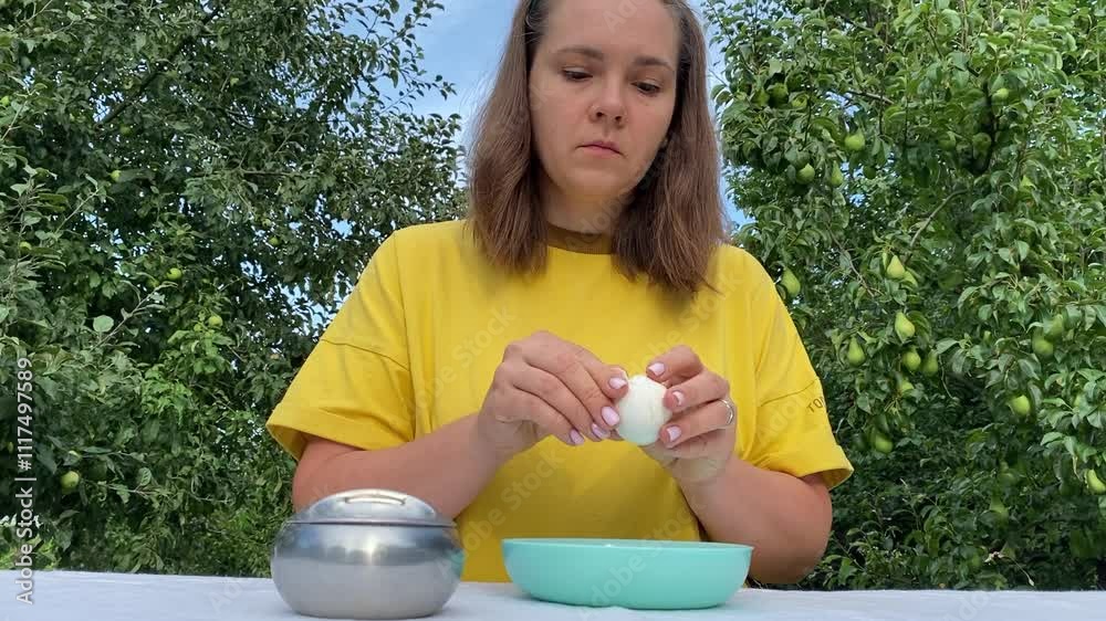 A beautiful young woman enjoys a casual lunch outdoors in a lush green park surrounded by trees. Relaxing and savoring her meal, she takes a moment to unwind in the fresh air and nature.