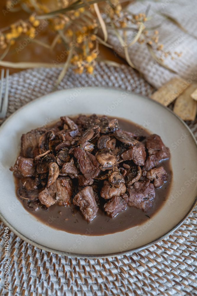 plate of meat with wine sauce on a wooden table in a house plate of meat with wine sauce on a wooden table in a house