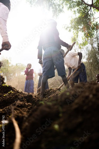 Children planting a tree in a rural African setting, surrounded by dry soil and greenery. The scene captures a moment of teamwork and environmental awareness, symbolizing growth and hope.