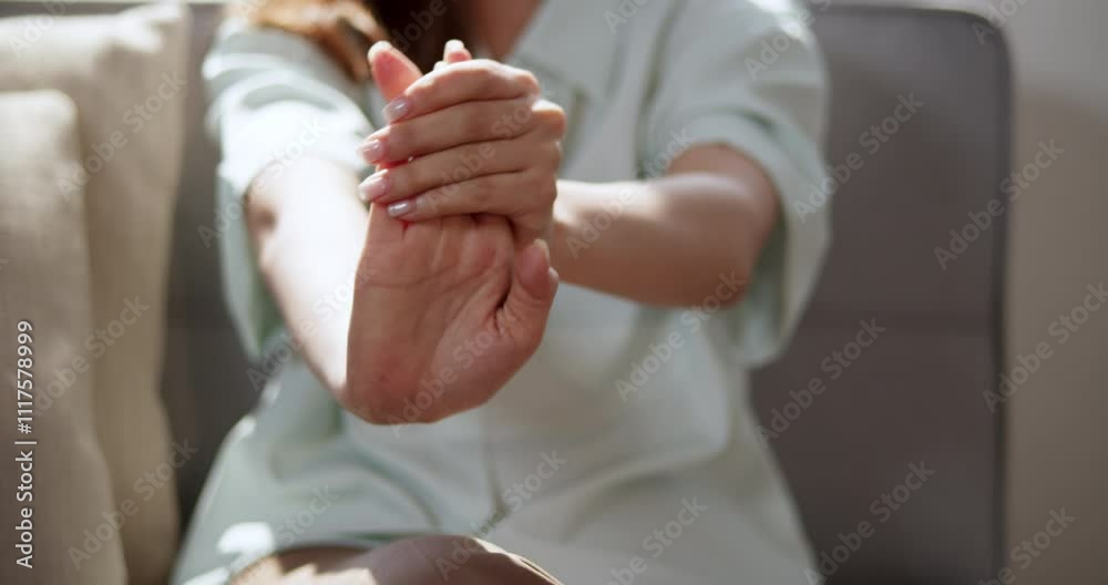 Close-up of a woman massaging her hands on the sofa to reduce inflammation, relax muscles, and relieve pain. A simple therapy for physical comfort.