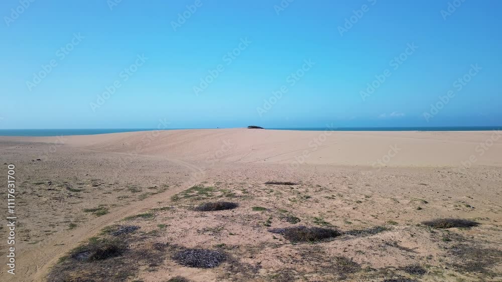 Wide aerial overview of La Guajira desert meeting the coastline under a bright blue sky Wide aerial overview of La Guajira desert meeting the coastline under a bright blue sky