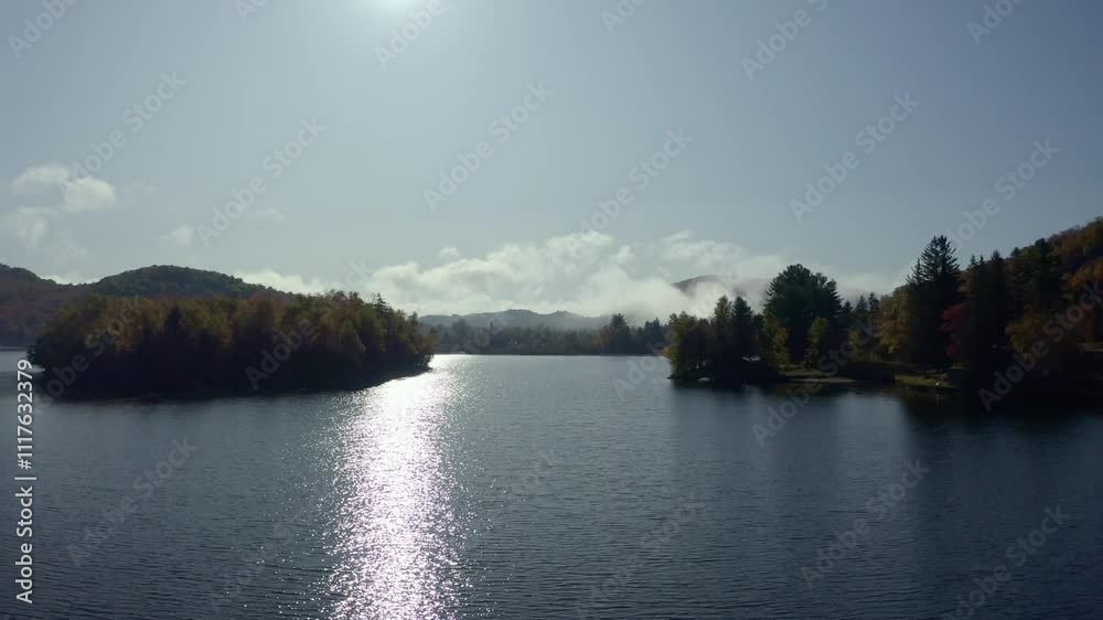 A tranquil lake under soft autumn light, featuring sparkling reflections and mist rolling over distant tree-covered hills, creating a serene and peaceful atmosphere. A tranquil lake under soft autumn light, featuring sparkling reflections and mist rolling over distant tree-covered hills, creating a serene and peaceful atmosphere.
