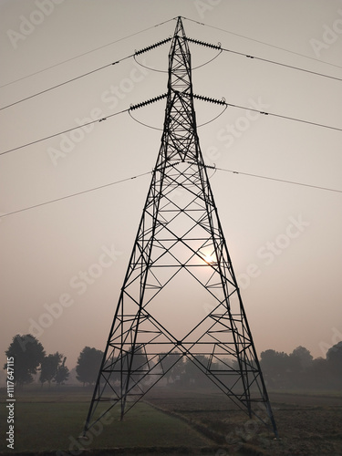 morning in Agricultural Field overlooking High Tension Electric Tower. Electricity concept, Close up high voltage power lines station. High voltage electric transmission pylon silhouetted tower.