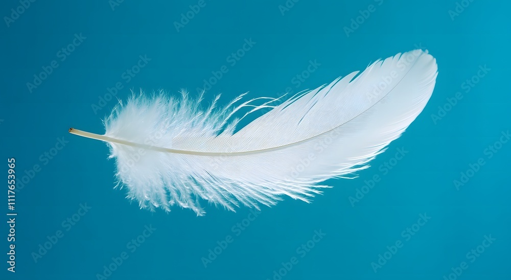 Obraz premium A single floating white feather floats in the air against a light blue background, highlighting the softness of the feather. Representing a feeling of calm and tranquility. It looks very beautiful.