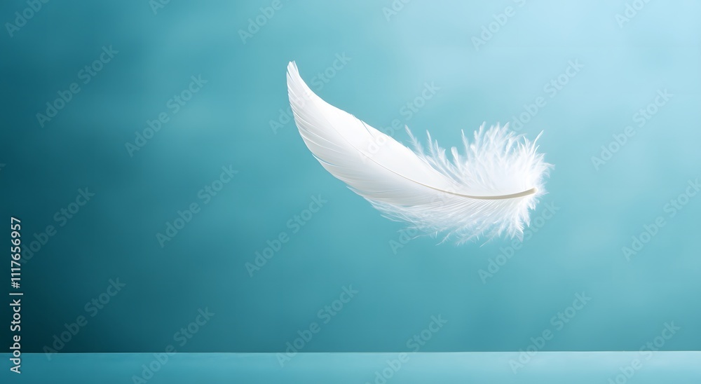 Obraz premium A single floating white feather floats in the air against a light blue background, highlighting the softness of the feather. Representing a feeling of calm and tranquility. It looks very beautiful.