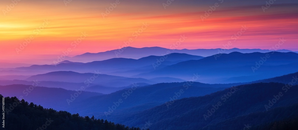 Obraz premium Colorful sunset over a mountain range with layers of mist and fog.