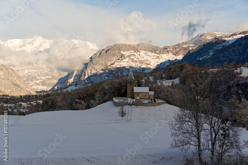 Scenic view of snowy landscape with St. Cassian church on a hill at Hinterrhein Valley in the Swiss Alps on sunny autumn day. Photo taken November 22nd, Sils im Domleschg, Switzerland. photo