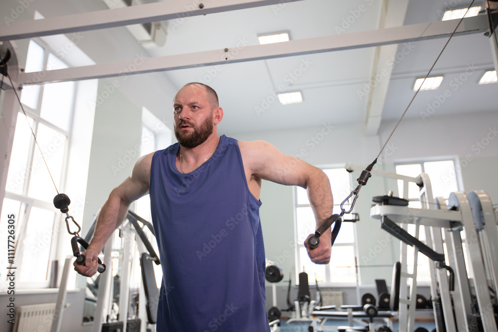Male athlete bodybuilder exercising in the gym. Strength training on a cable machine. Male athlete bodybuilder exercising in the gym. Strength training on a cable machine.
