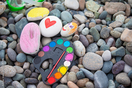 Concept of creativity. Brightly painted stones and a brush on grey sea pebbles.