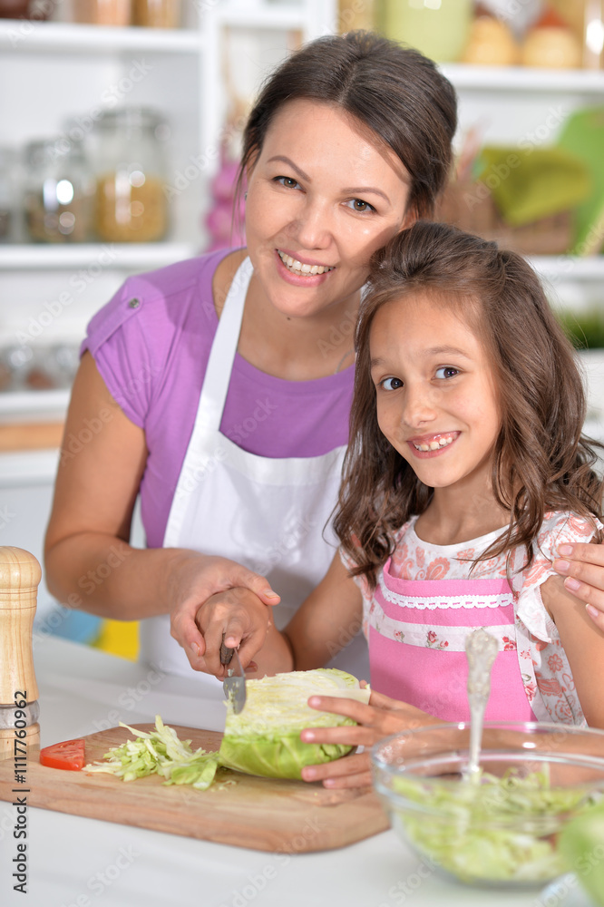Mother and daughter preparing salad with daughter in the kitchen Mother and daughter preparing salad with daughter in the kitchen