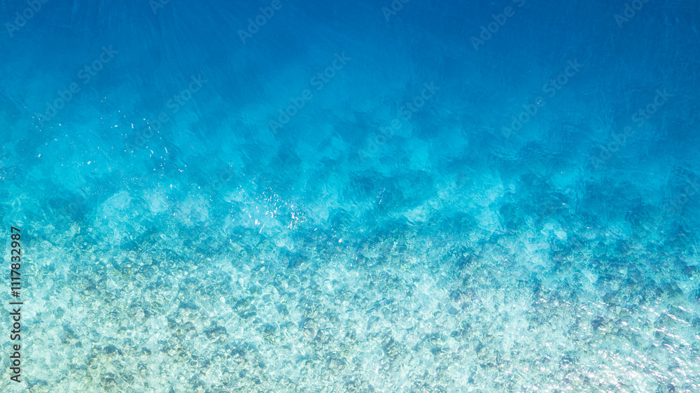 Top view of the turquoise gradient color of the water. The ocean is like a background. Incredible gradient from light blue to dark. Reef and fish swim. Clear water in the lagoon. The drone. Maldives