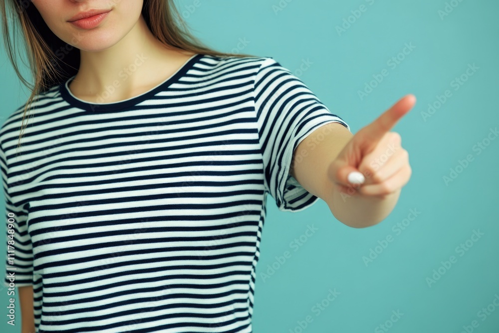 A woman wearing a striped shirt points at the camera, making eye contact