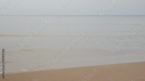 Baltic Sea, sandy shore with small waves and calm water on a cloudy day