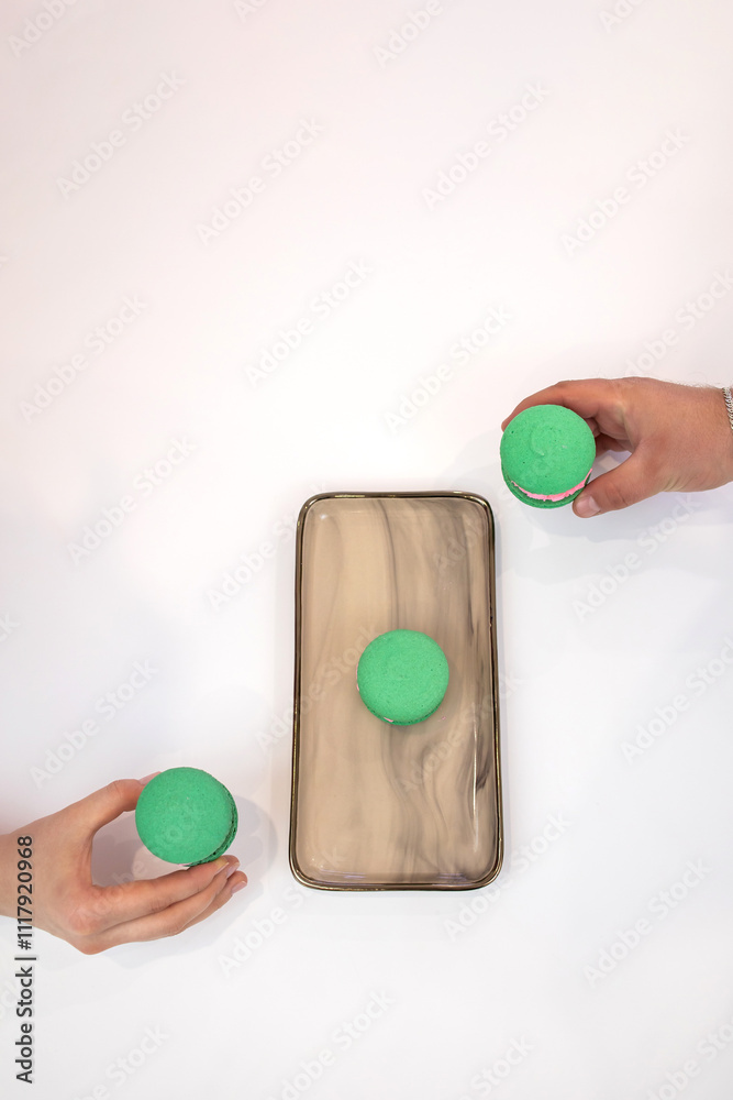 Green macaroons. Sweets. Pink filling for macaroons. Delicious pastries. Hands take macaroons Green macaroons. Sweets. Pink filling for macaroons. Delicious pastries. Hands take macaroons