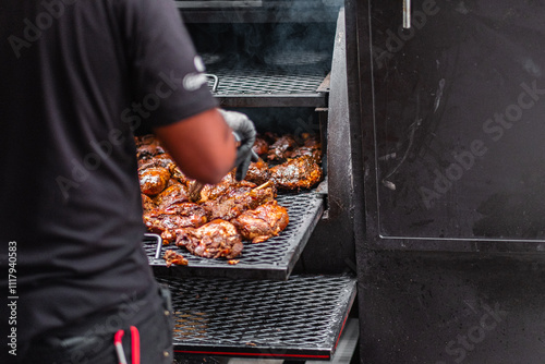 Fotografia Man Grilling Juicy Barbecue Chicken in Outdoor Smoker Oven with Smoky Flavor on