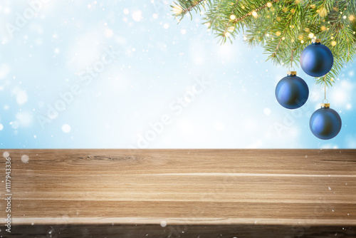 Empty wood table with blue Christmas baubles and fir tree branch on snowy blue background. Winter holiday backdrop with copy space. Template for product placement and advertising