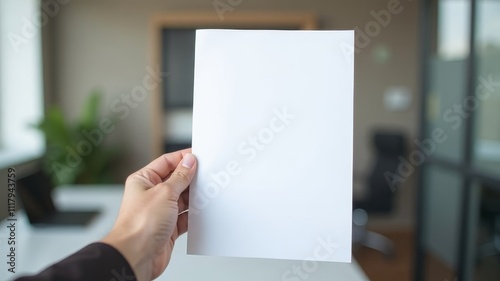 Hand holding white A4 sheet in office